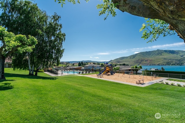 view of nearby features with a lawn, a swimming pool, a playground, and a water and mountain view