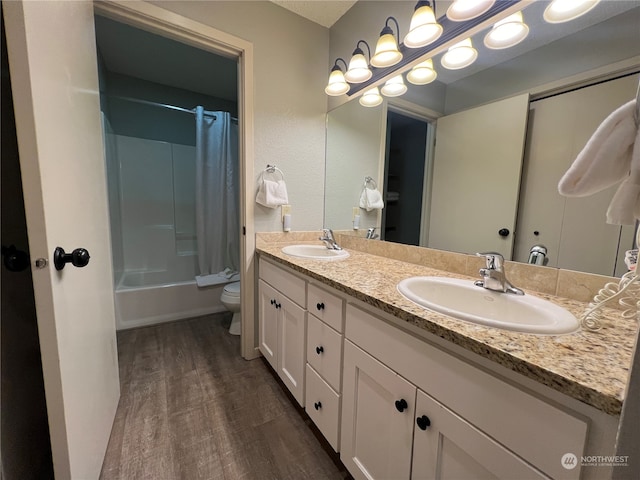 full bathroom featuring vanity with extensive cabinet space, wood-type flooring, shower / bath combo, double sink, and toilet