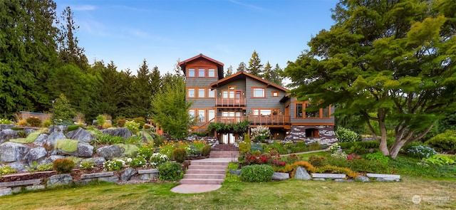 back of property with a wooden deck and a lawn