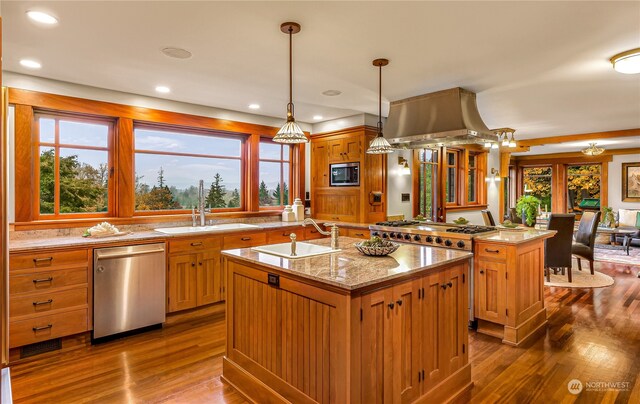 kitchen featuring appliances with stainless steel finishes, a center island with sink, wood-type flooring, sink, and pendant lighting