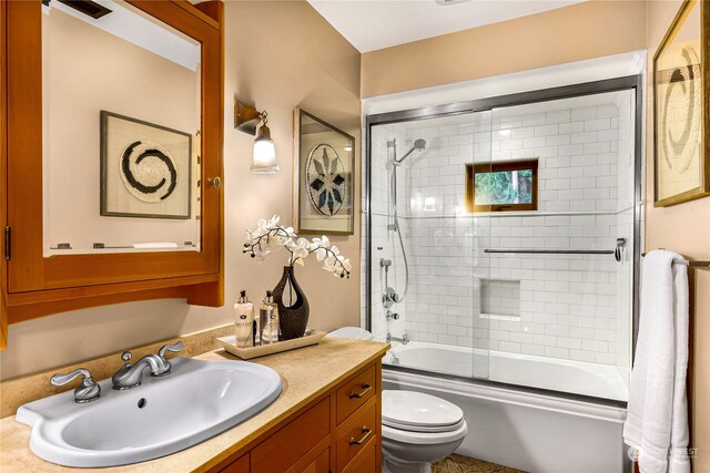 full bathroom featuring vanity, toilet, and bath / shower combo with glass door