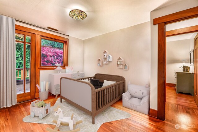 bedroom featuring wood-type flooring and a crib