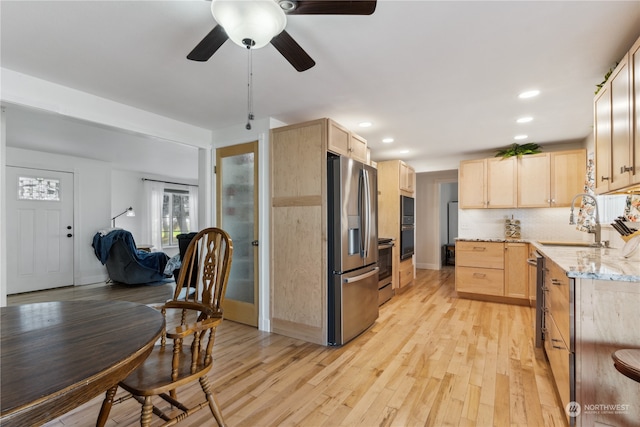 kitchen with light brown cabinetry, ceiling fan, light wood-type flooring, and stainless steel appliances