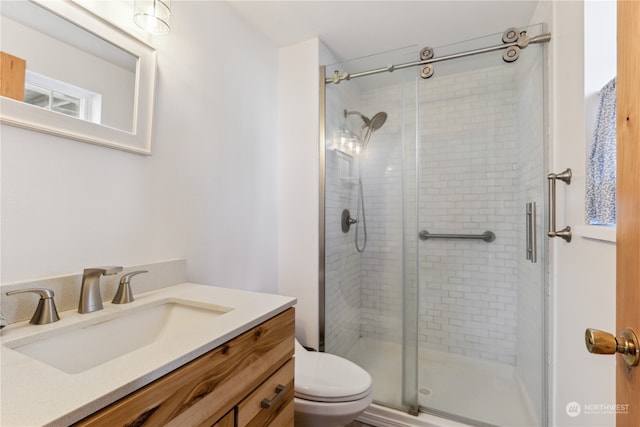 bathroom featuring vanity, toilet, and a shower with shower door