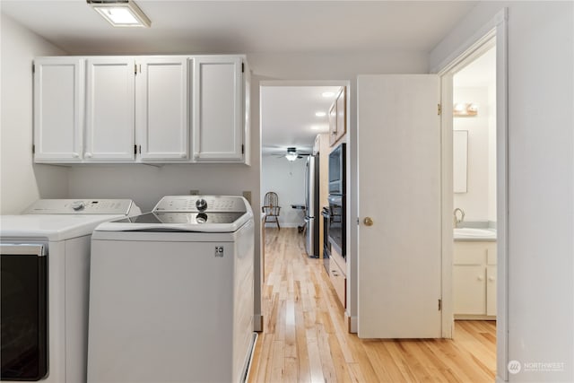 clothes washing area featuring washer and clothes dryer, light hardwood / wood-style floors, cabinets, and sink