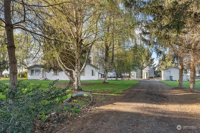 view of front of property featuring an outdoor structure, a garage, and a front yard