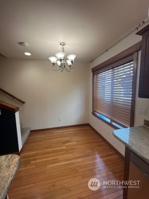 unfurnished dining area featuring light wood-type flooring and a chandelier