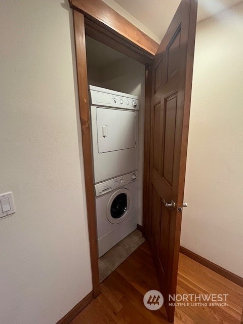 laundry room with wood-type flooring and stacked washer and dryer