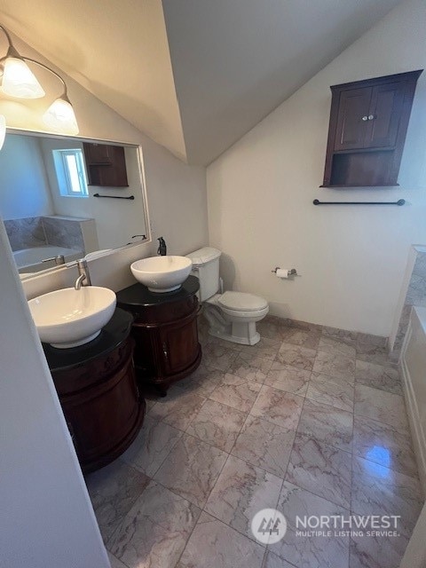 bathroom featuring tile floors, large vanity, a bathing tub, toilet, and lofted ceiling