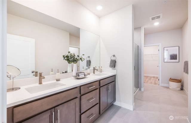 bathroom with dual vanity, an enclosed shower, and tile patterned floors