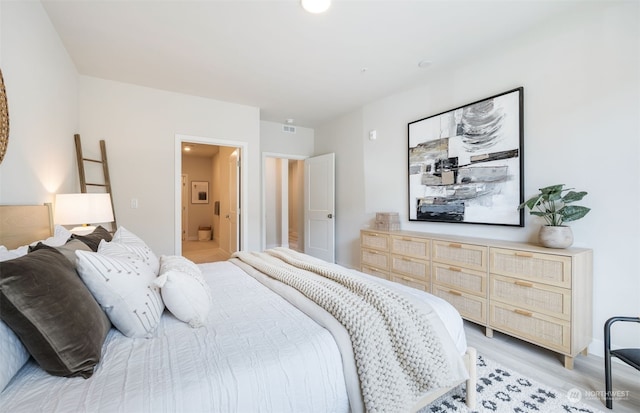 bedroom with light hardwood / wood-style flooring and ensuite bath