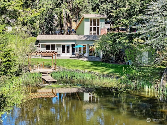 back of property featuring a patio area, a water view, a pergola, and a lawn