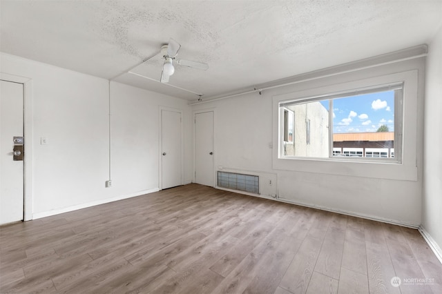 spare room featuring ceiling fan, light hardwood / wood-style flooring, and a textured ceiling