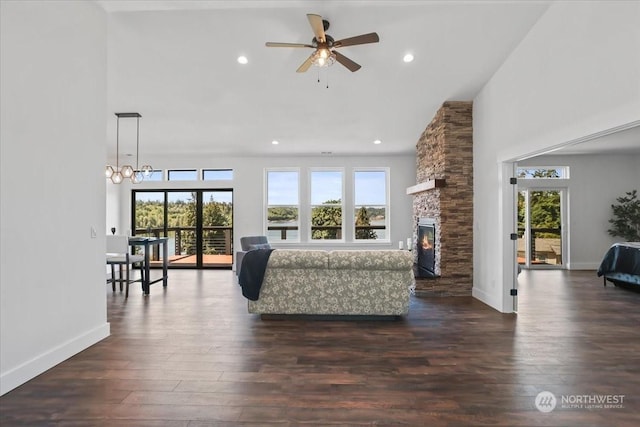 living room with dark hardwood / wood-style flooring, a fireplace, and ceiling fan with notable chandelier