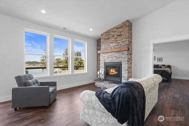 living room featuring a stone fireplace, dark wood-type flooring, and vaulted ceiling