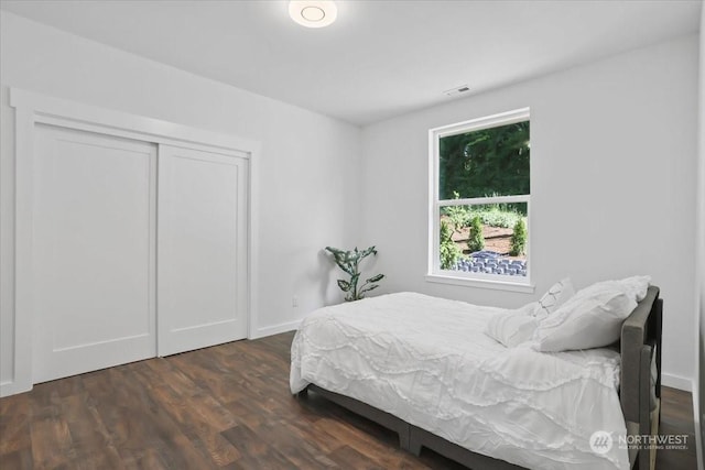 bedroom with dark hardwood / wood-style floors and a closet