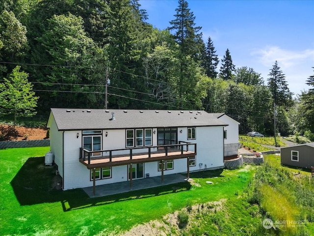 rear view of property with a yard, a patio, and a deck