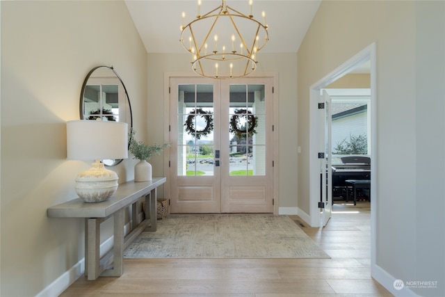 entryway with french doors, light hardwood / wood-style floors, and a notable chandelier