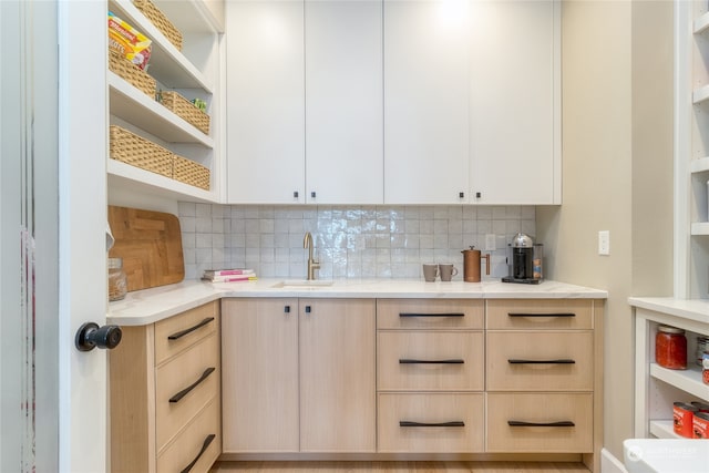 kitchen with sink, light stone counters, backsplash, and light brown cabinetry