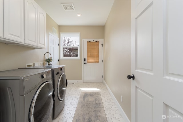 clothes washing area featuring cabinets, separate washer and dryer, and light tile patterned floors