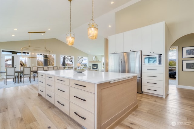 kitchen featuring decorative light fixtures, light hardwood / wood-style flooring, stainless steel appliances, and a spacious island