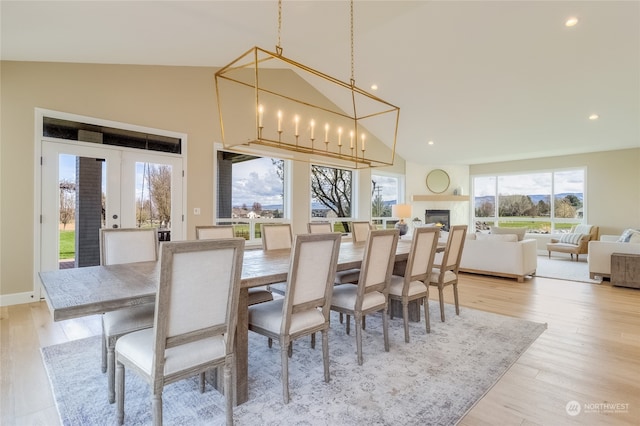 dining space featuring french doors, high vaulted ceiling, light wood-type flooring, and a wealth of natural light