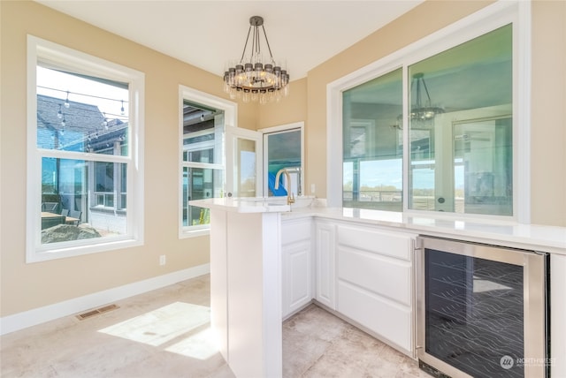 bar featuring wine cooler, pendant lighting, a wealth of natural light, and white cabinets