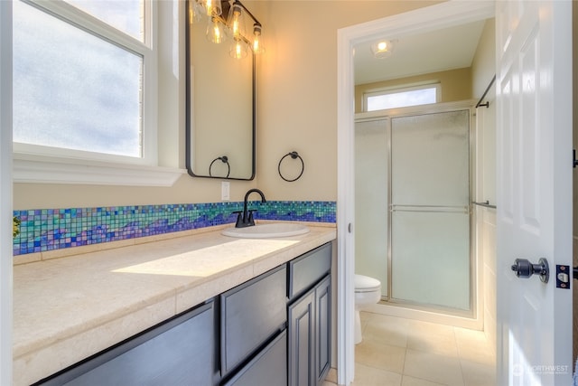 bathroom featuring backsplash, tile patterned flooring, vanity, toilet, and a shower with door