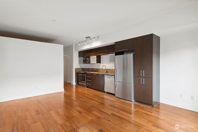 kitchen with appliances with stainless steel finishes, light hardwood / wood-style floors, dark brown cabinets, and sink