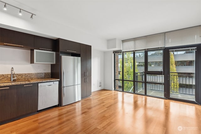 kitchen with dark brown cabinetry, stainless steel fridge, sink, and white dishwasher