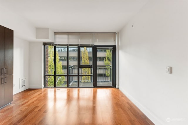 unfurnished room with light hardwood / wood-style flooring and a wall of windows