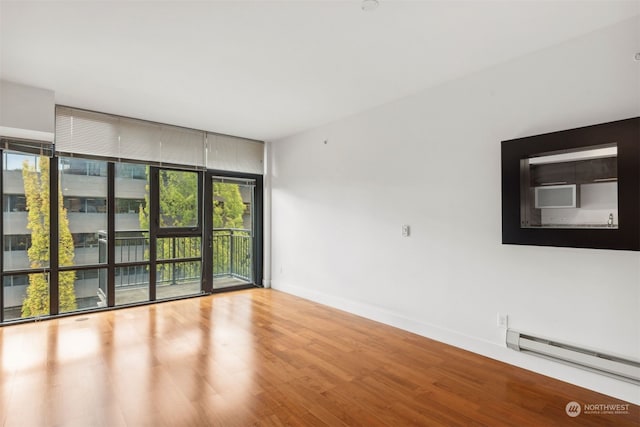 spare room featuring light wood-type flooring, baseboard heating, and expansive windows