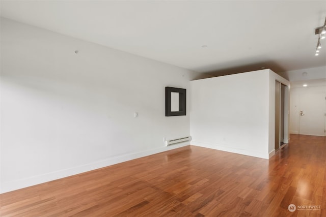 empty room with hardwood / wood-style floors and a baseboard radiator