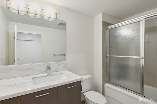 full bathroom with toilet, combined bath / shower with glass door, and vanity