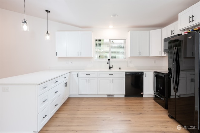 kitchen featuring sink, light wood-type flooring, pendant lighting, and black appliances