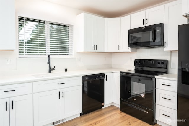 kitchen featuring a sink, visible vents, white cabinets, light countertops, and black appliances