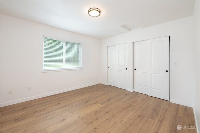 unfurnished bedroom with light hardwood / wood-style floors and two closets