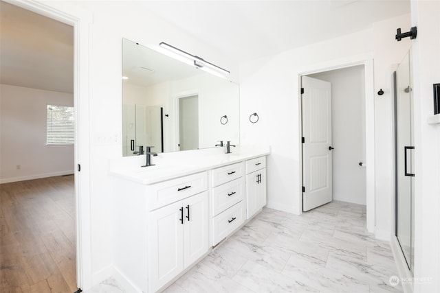 full bath with a stall shower, marble finish floor, a sink, and double vanity