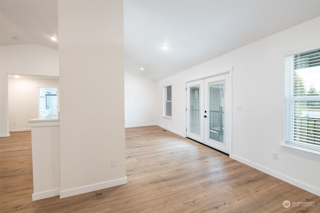 spare room featuring french doors, light hardwood / wood-style floors, and vaulted ceiling