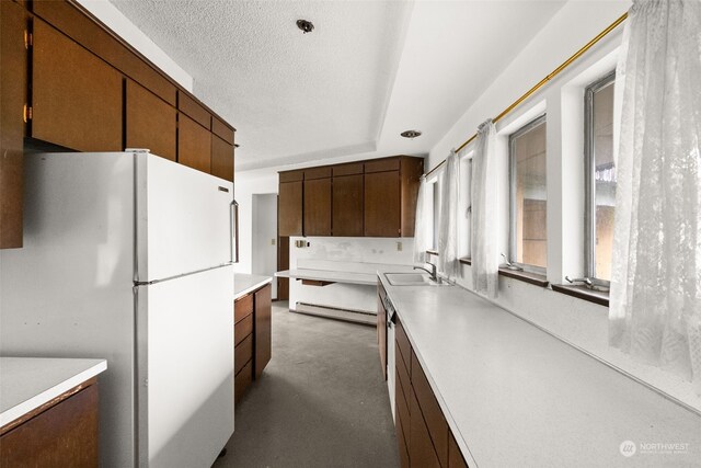 kitchen with a textured ceiling, white refrigerator, and sink