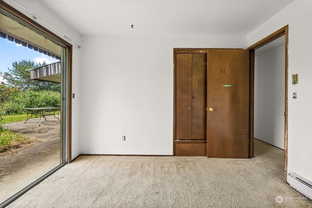 unfurnished room with light colored carpet and a baseboard heating unit