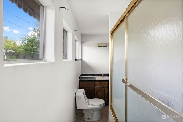 bathroom with tile patterned flooring, vanity, toilet, and a shower with shower door