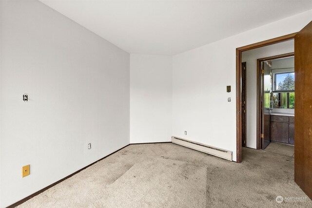 carpeted spare room featuring baseboard heating