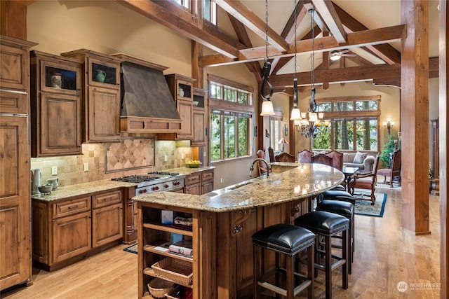 1450 Pinegrass Loop, Cle Elum, WA 98922 - kitchen with custom exhaust hood, stainless steel stove, beamed ceiling, light stone countertops, and decorative backsplash