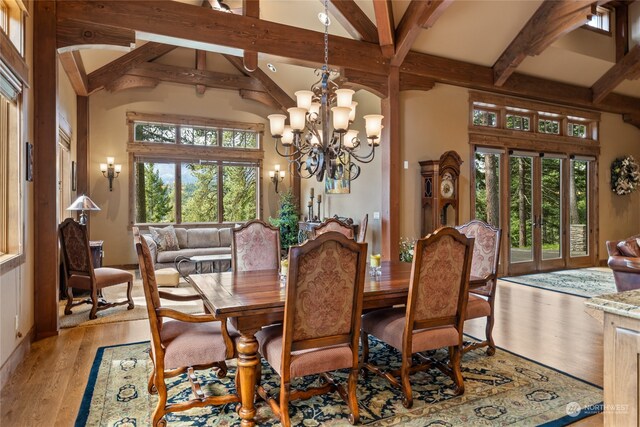 dining room with beam ceiling, plenty of natural light, an inviting chandelier, and light hardwood / wood-style flooring