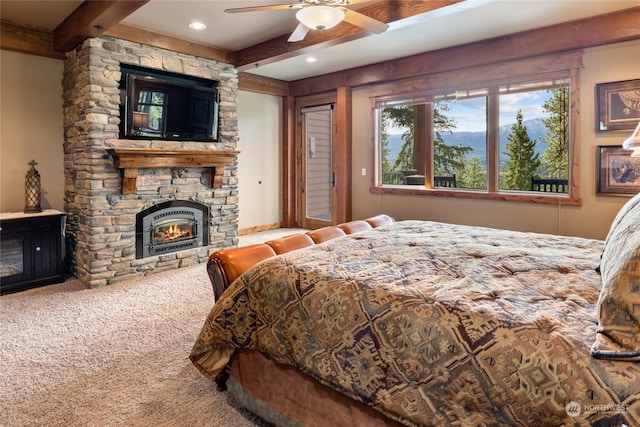 carpeted bedroom featuring a fireplace, beam ceiling, and ceiling fan