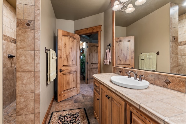 bathroom featuring a tile shower, vanity, and an inviting chandelier