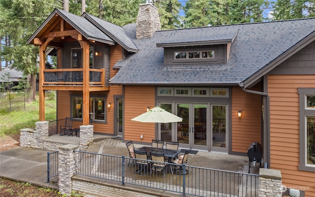 rear view of property with french doors, a balcony, and a patio