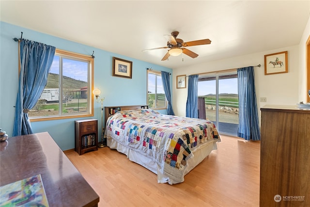 bedroom featuring ceiling fan, light hardwood / wood-style floors, access to outside, and multiple windows