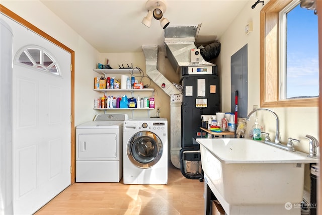 clothes washing area with washing machine and clothes dryer, sink, and light wood-type flooring